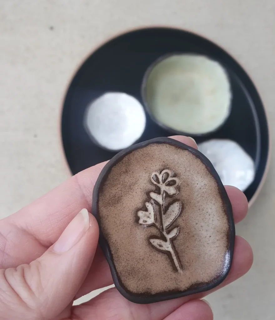 Mayco Alabaster performs on black stoneware with impressed texture. A Cone 6 glaze test showing soft cream tones, beautiful glaze breaking, and natural contrast.
