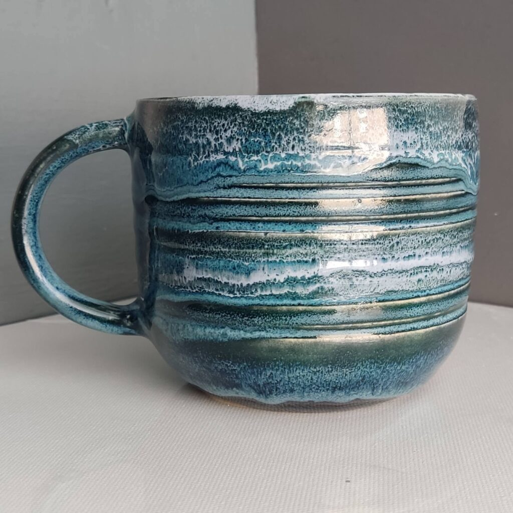 Side view of Snow over Teal Drift over Obsidian Cone 6 glaze combination